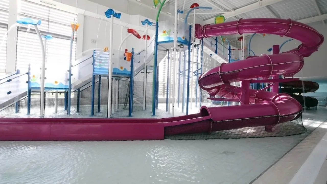 Indoor water play area at South Lake Leisure Centre with colourful splash features and bright pink spiral waterslide