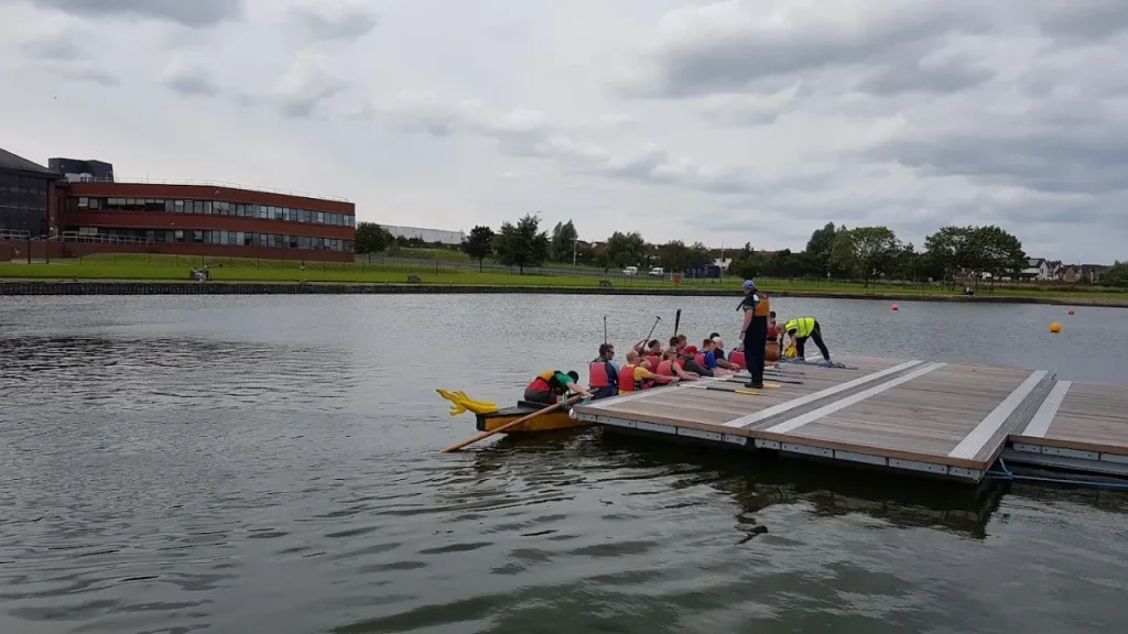 People preparing to paddle a dragon boat from a floating dock at South Lake Leisure Centre watersports lake