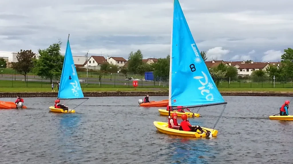 Children sailing yellow dinghies with blue sails during a beginner sailing session at South Lake Leisure Centre Watersports