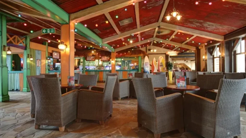 Tropical-inspired lounge at Splash Landings Hotel featuring rattan seating, colourful ceiling lights, and surfboard decorations — a fun, beachy retreat and one of our featured places to stay to Alton Towers.