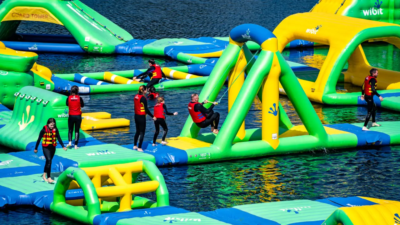 Families and children navigating inflatable climbing frames and balance obstacles at Splash Outdoor Waterpark AquaPark in Northern Ireland.