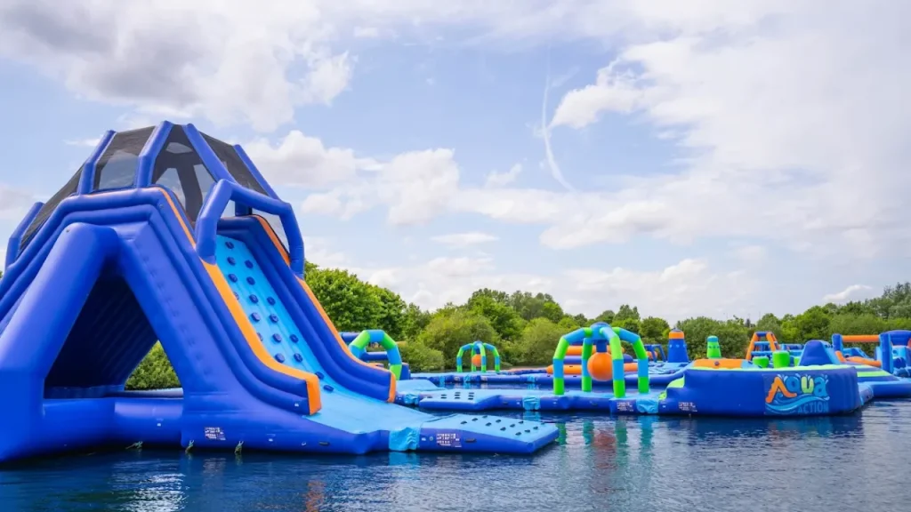 Close-up of the tall inflatable climbing wall and drop slide at Aqua Action Fairlop Waters inflatable water park in London.