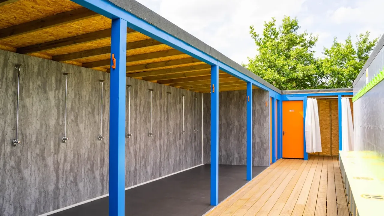 Row of open outdoor showers at Aqua Action inflatable water park in Fairlop Waters, London.