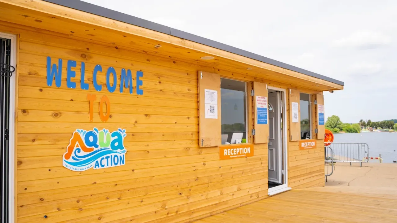 Wooden reception building with Aqua Action signage and welcome board at Fairlop Waters Country Park.