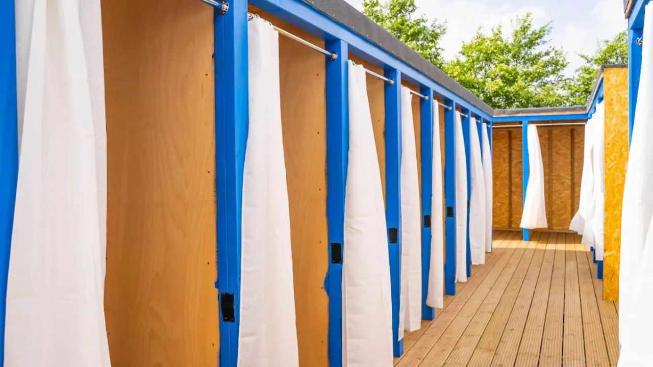 Row of private wooden changing rooms with curtains at Aqua Action Fairlop water park.