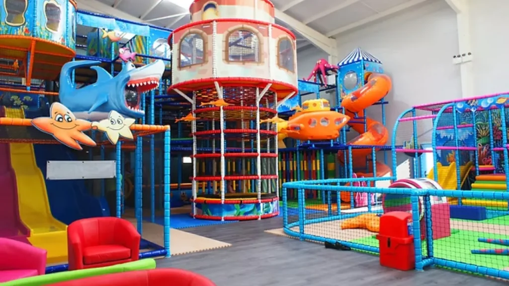Bright and colourful indoor soft play area at Brean Play featuring slides, climbing frames, padded flooring, and ocean-themed decorations.