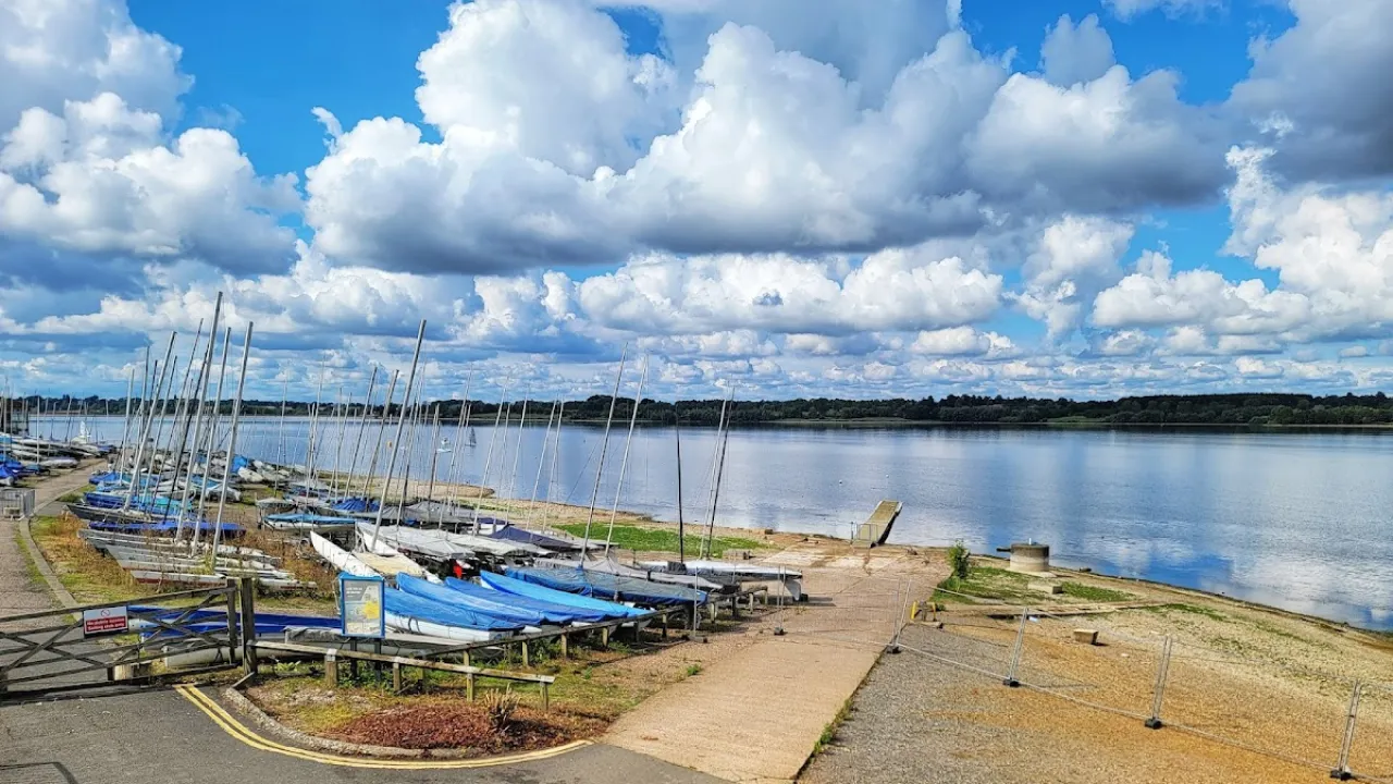 Rows of sailboats on the shore of Draycote Water beside a calm reservoir.