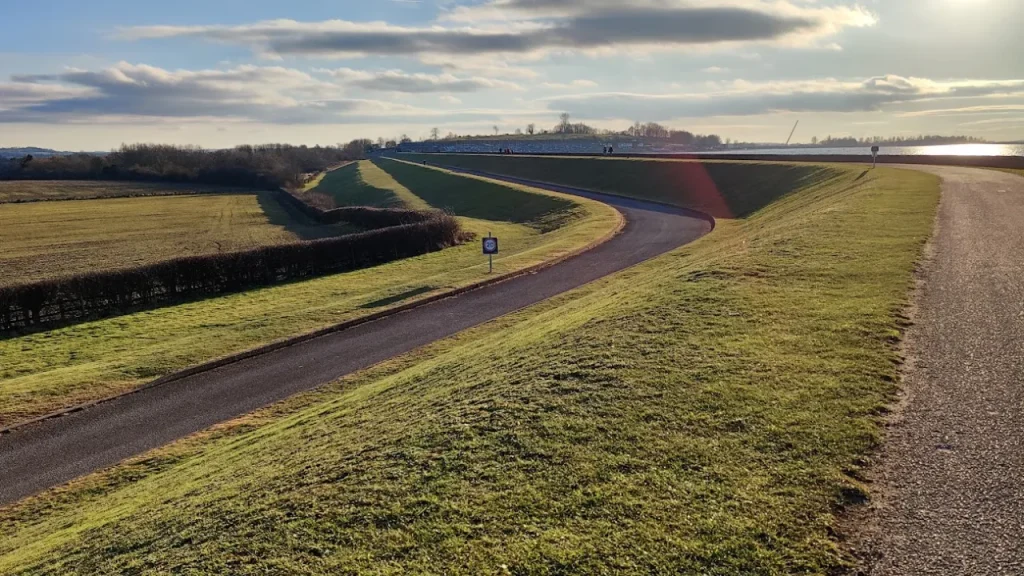 Curving paved trail surrounded by grassy fields at Draycote Water reservoir.