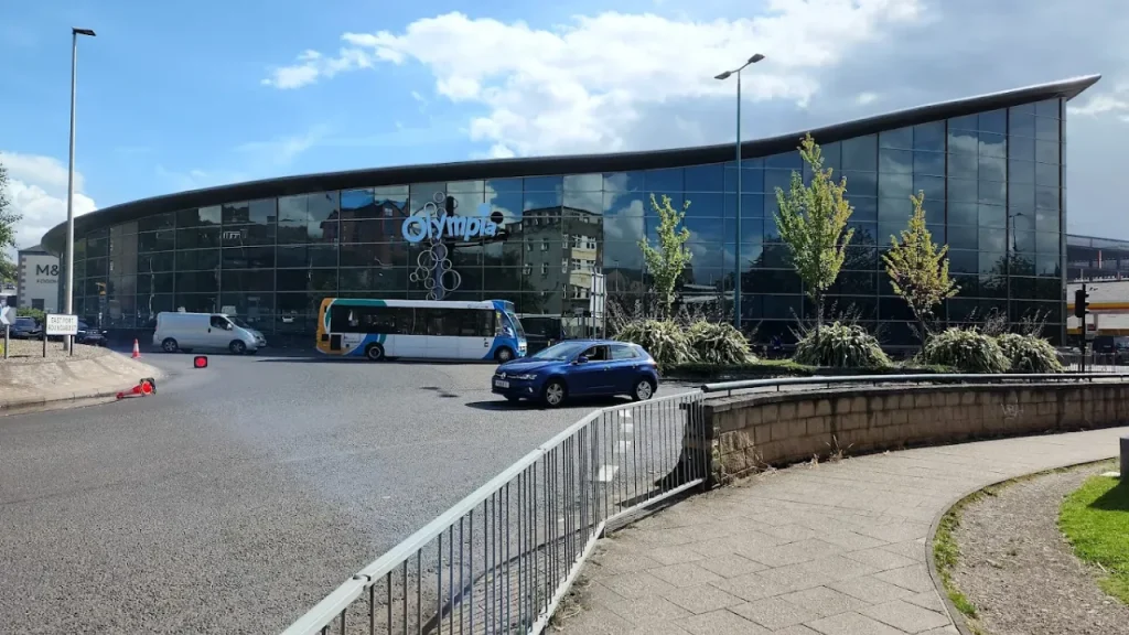 Exterior view of Dundee Olympia Leisure Centre with bus and cars at the roundabout in Dundee city centre.