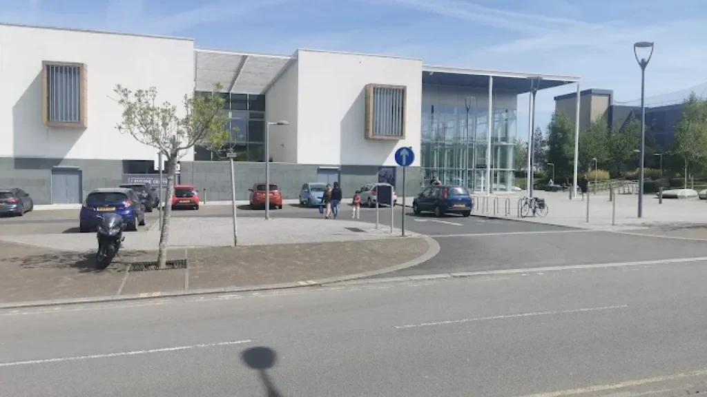 Front car park and glass entrance of Hengrove Park Leisure Centre with visible cycle storage and footpath.