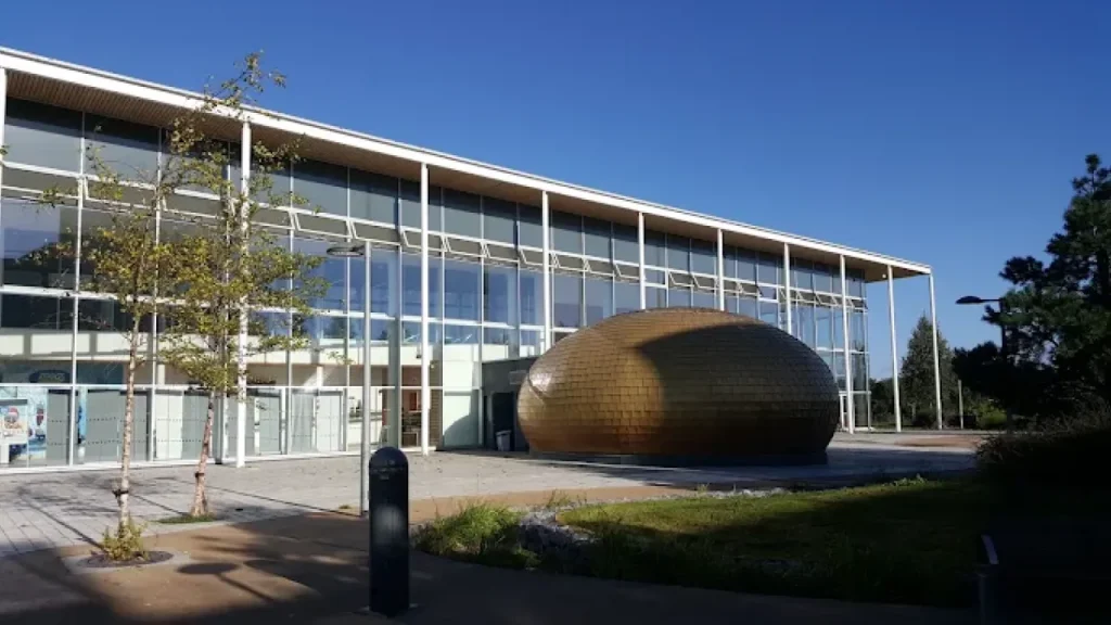 Bronze pod structure and front facade of Hengrove Park Leisure Centre on a sunny day.