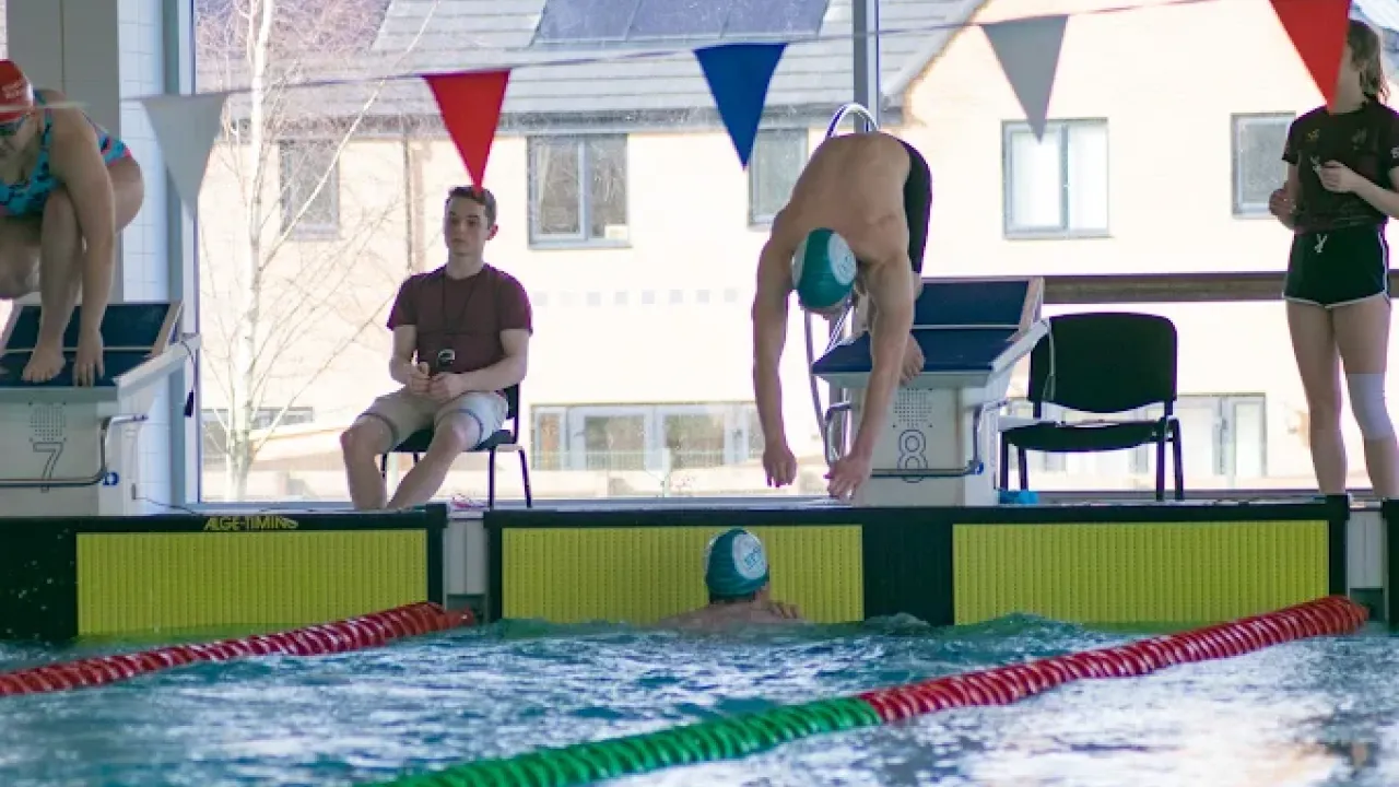 Swimmer diving into the pool while others watch at Hengrove Park Leisure Centre in Bristol.