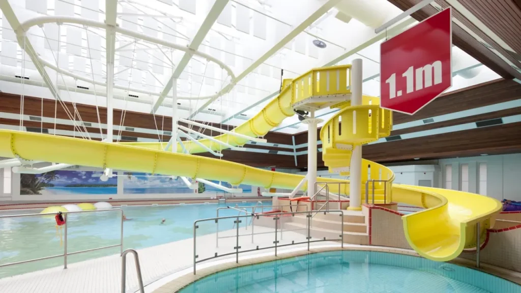 Yellow indoor flume slide inside Lagoon Leisure Centre leisure pool with height sign visible.