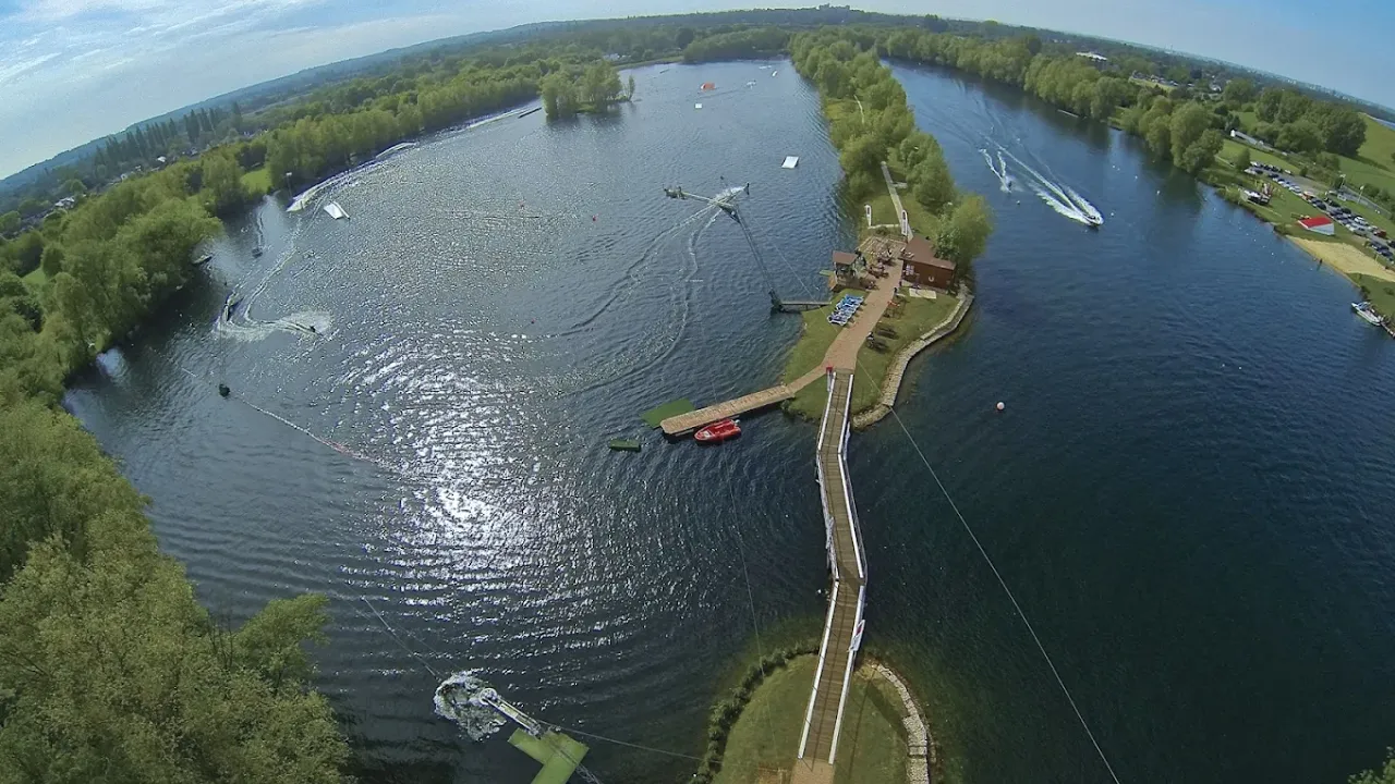 Drone view of Liquid Leisure Aqua Park showing large lake, cable systems, docks, and surrounding forest.