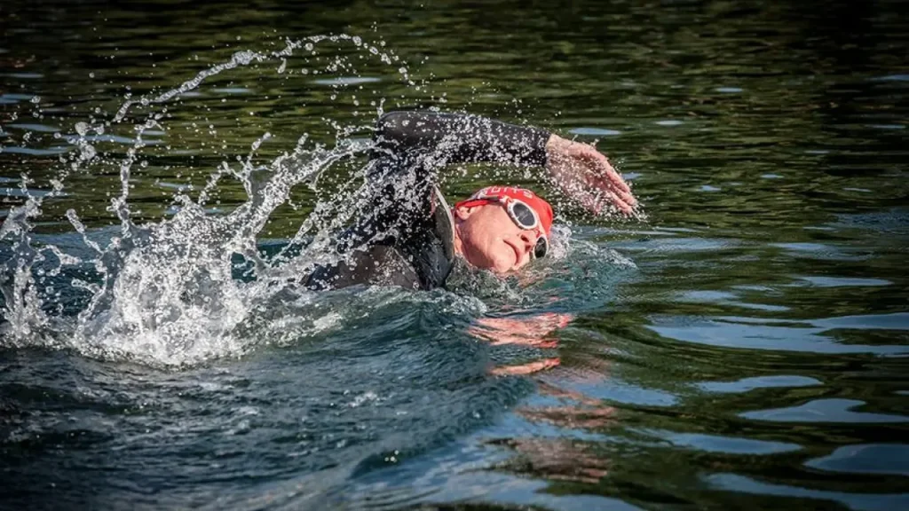Open-water swimmer in wetsuit and goggles at Liquid Leisure Aqua Park during outdoor swim session.