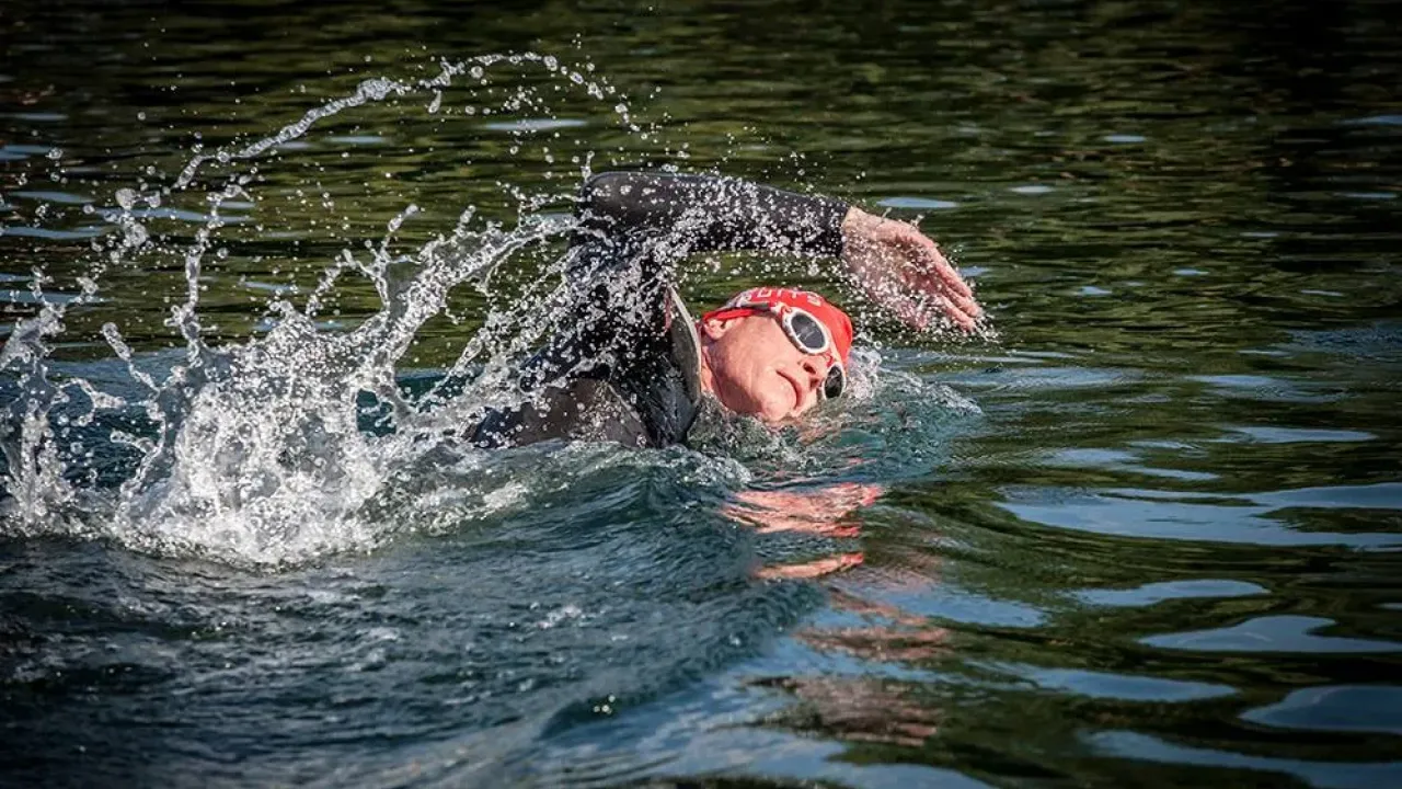Open-water swimmer in wetsuit and goggles at Liquid Leisure Aqua Park during outdoor swim session.