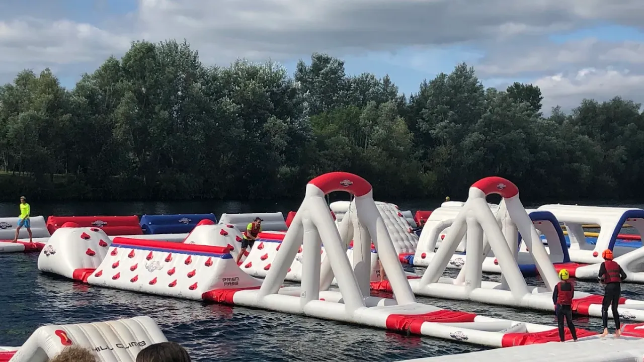 Red and white inflatable aqua park structure at Liquid Leisure surrounded by safety barriers.