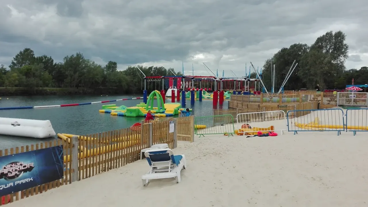 Inflatable aqua park course with green and yellow obstacles at Liquid Leisure, beside a beach area.