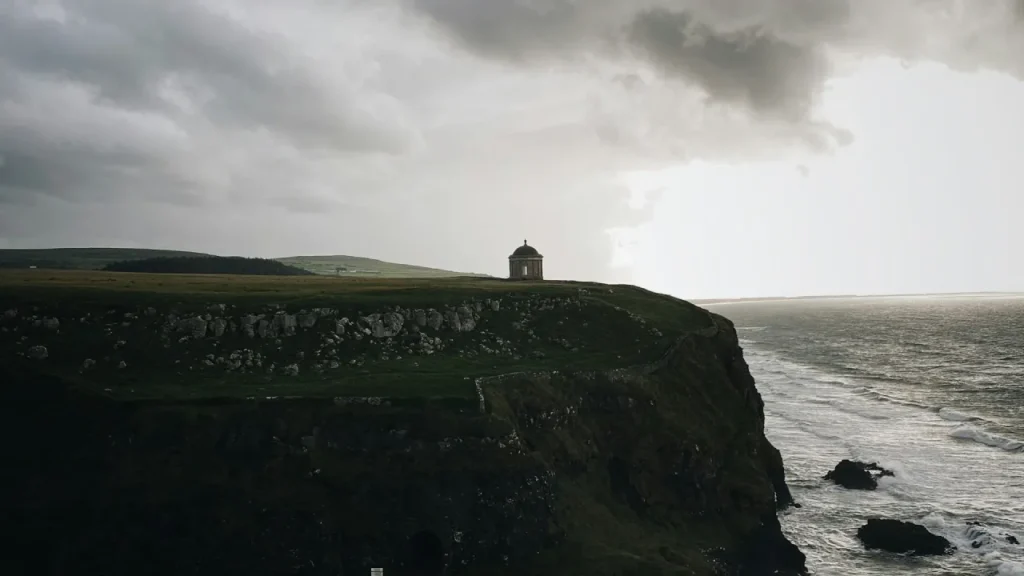 Mussenden Temple on a coastal cliff near Coleraine in County Londonderry, Northern Ireland, overlooking the Atlantic Ocean under dramatic skies.