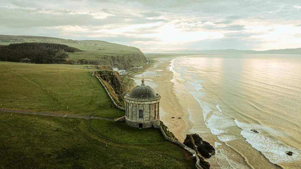 Aerial view from Mussenden Temple overlooking Castlerock Beach and the Atlantic Ocean in County Londonderry, Northern Ireland, with golden sand and coastal cliffs.