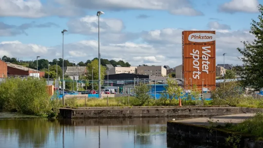 Front entrance of Pinkston Watersports centre in Glasgow, showing orange signage and pedestrian bridge.