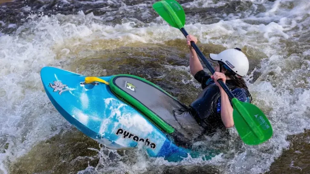Kayaker navigating rapids at Pinkston Watersports whitewater facility in Glasgow, Scotland.