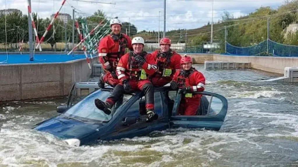 Emergency responders sitting on top of a submerged car during rescue training at Pinkston Watersports Glasgow.
