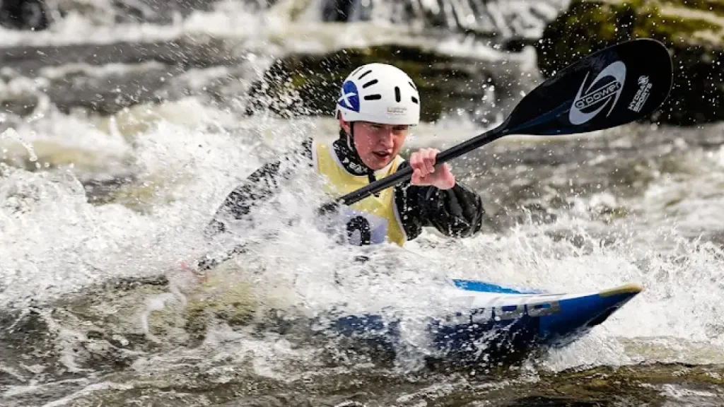 Close-up of a male kayaker racing through rough whitewater at Pinkston Watersports Glasgow.
