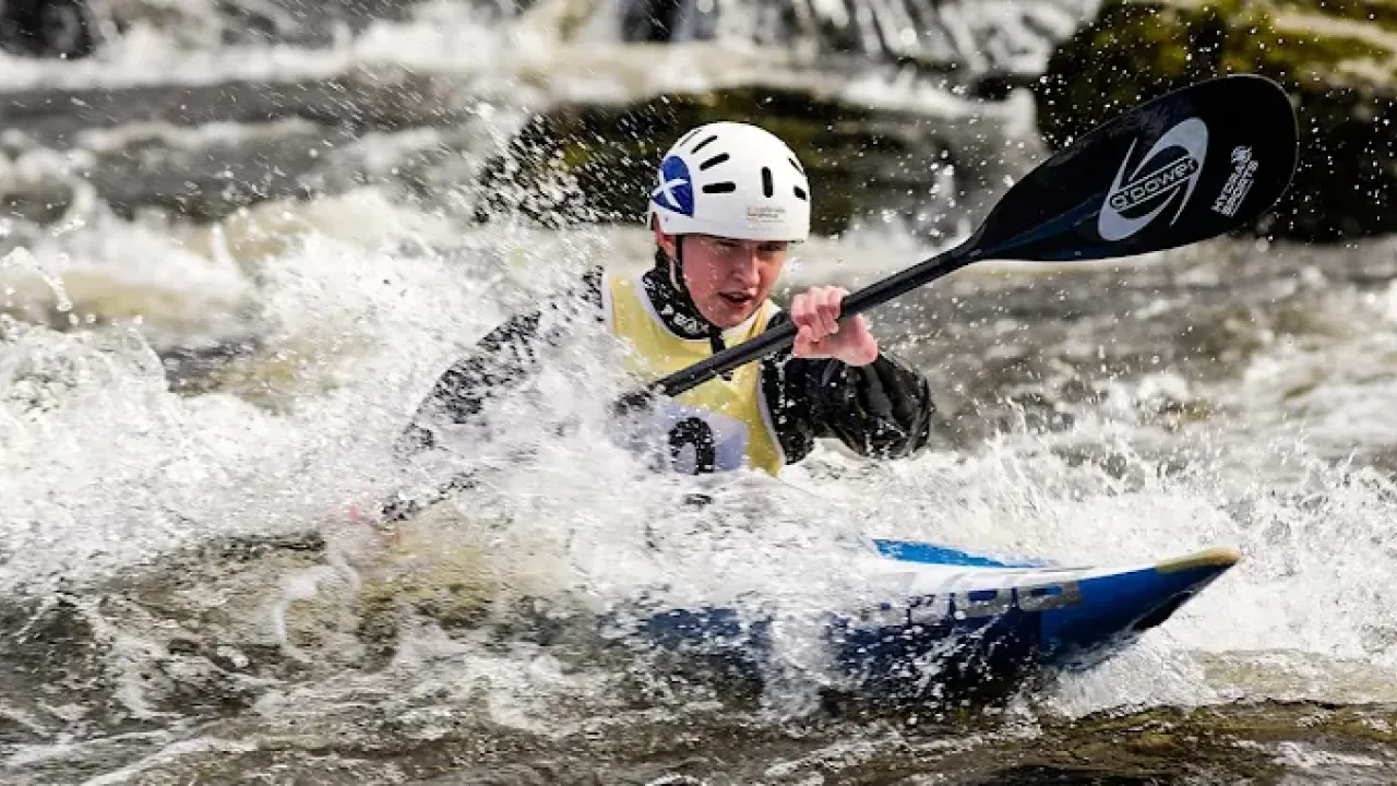 Close-up of a male kayaker racing through rough whitewater at Pinkston Watersports Glasgow.