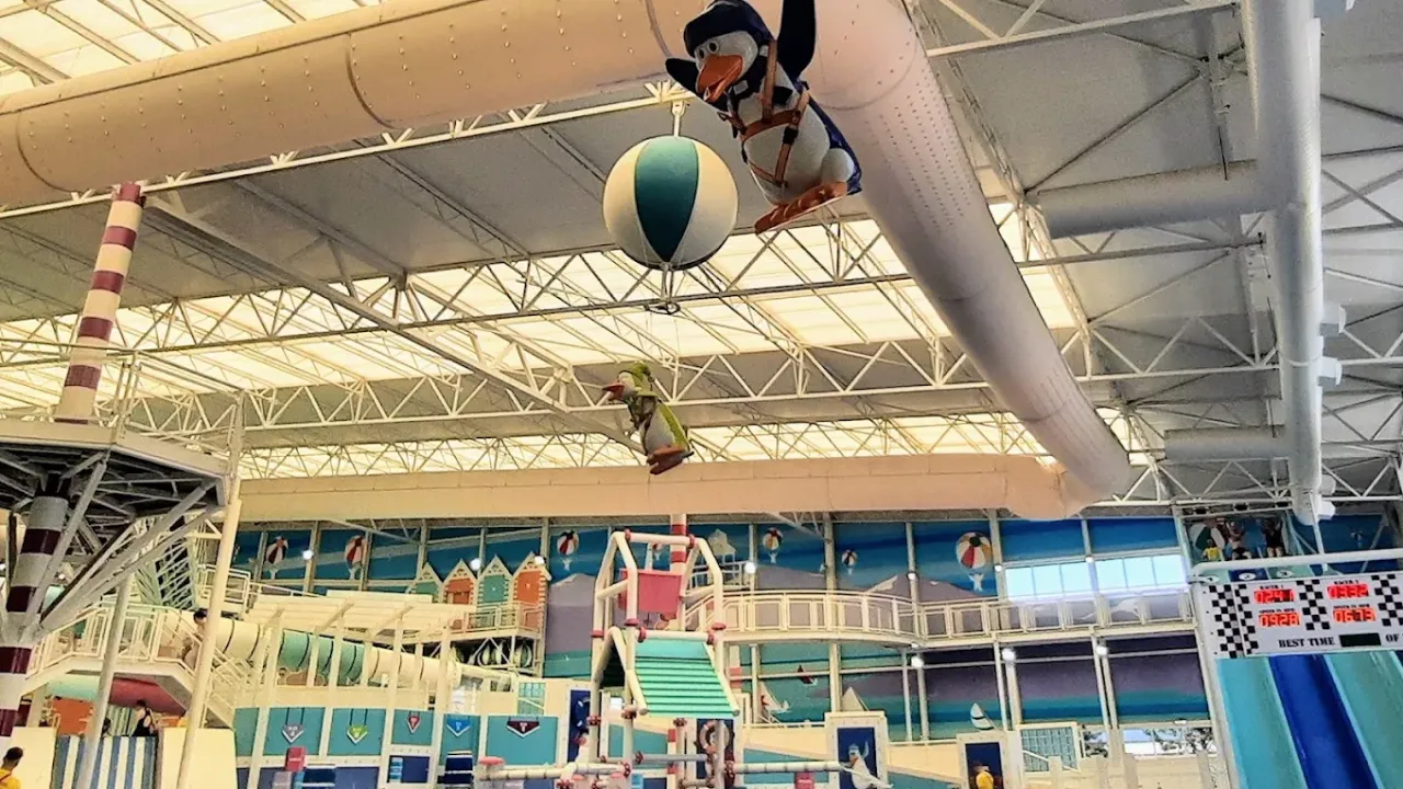Lazy river and splash area at Splashaway Bay with cartoon birds and beach balls hanging from ceiling beams.