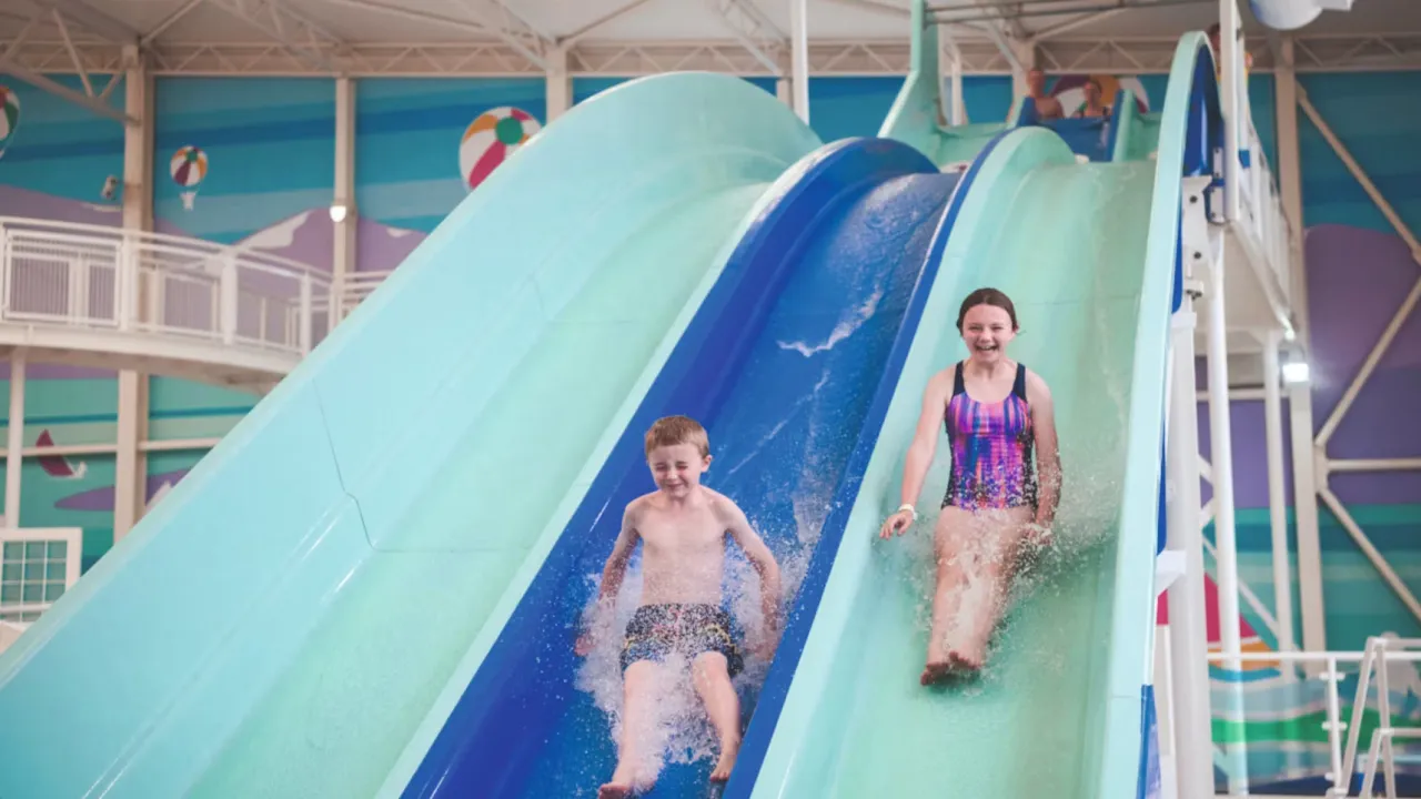 Kids enjoying the curved blue water slides at Splashaway Bay indoor water park.