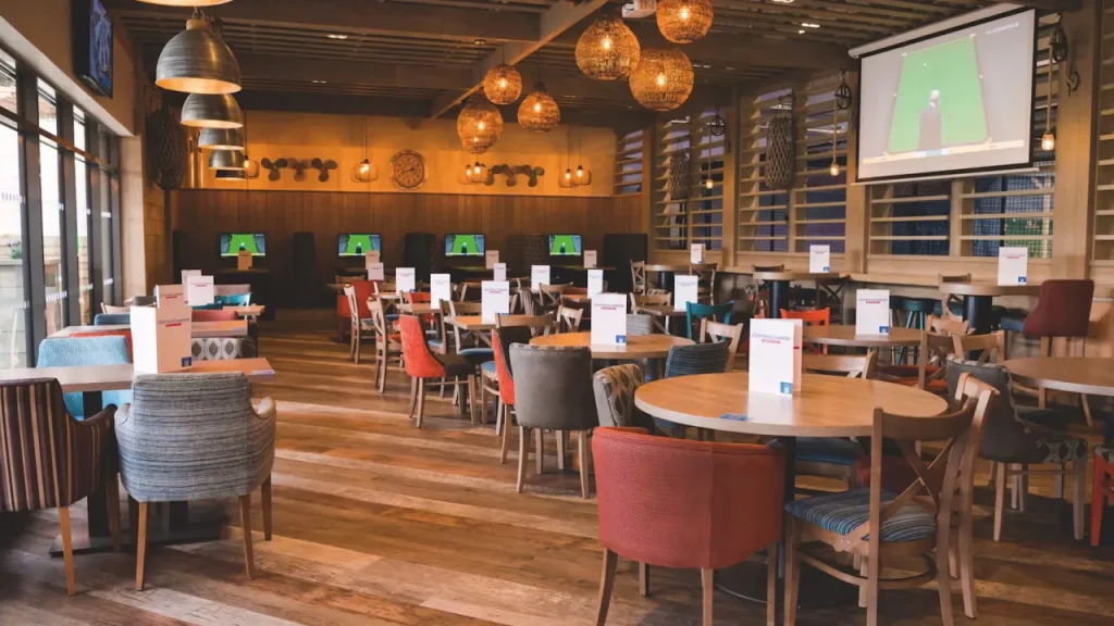 Restaurant seating area at Craig Tara Holiday Park near Splashaway Bay, with TVs and warm lighting.