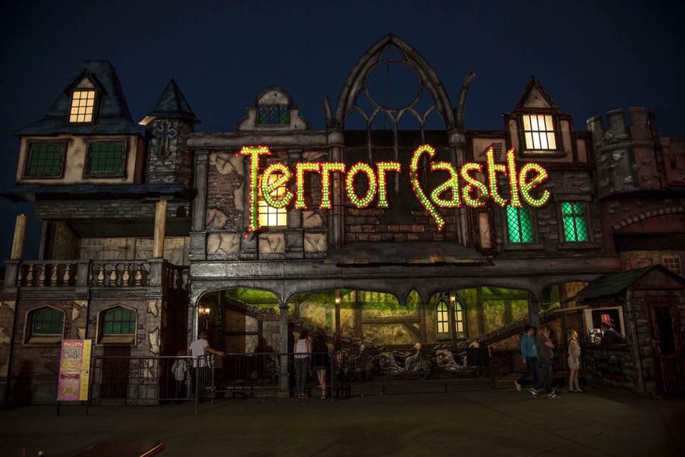 Front view of Terror Castle haunted house ride at Brean Theme Park, lit up at night with spooky gothic architecture and glowing signage.