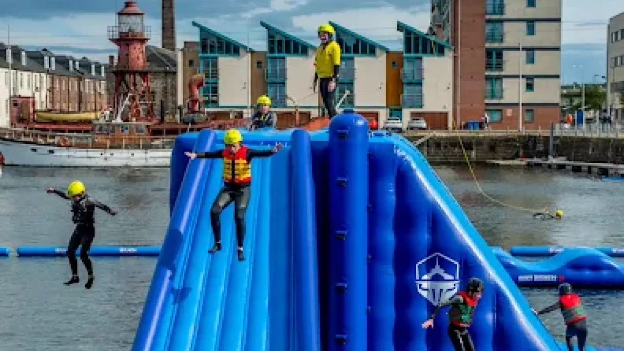 Participants sliding down a large inflatable structure at Wild Shore Dundee.
