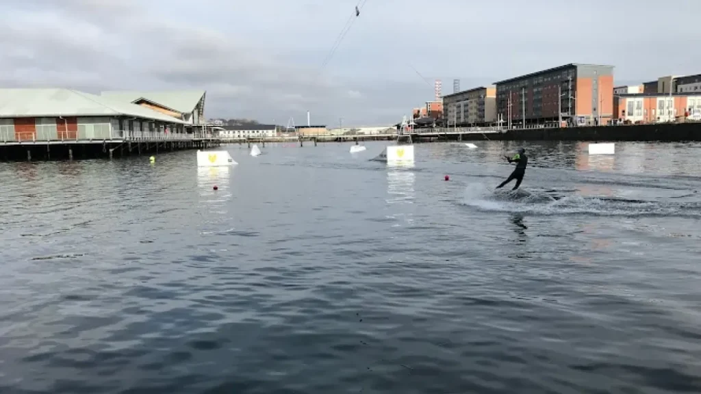 Wakeboarder gliding across City Quay at Wild Shore Dundee with water ramps in background.