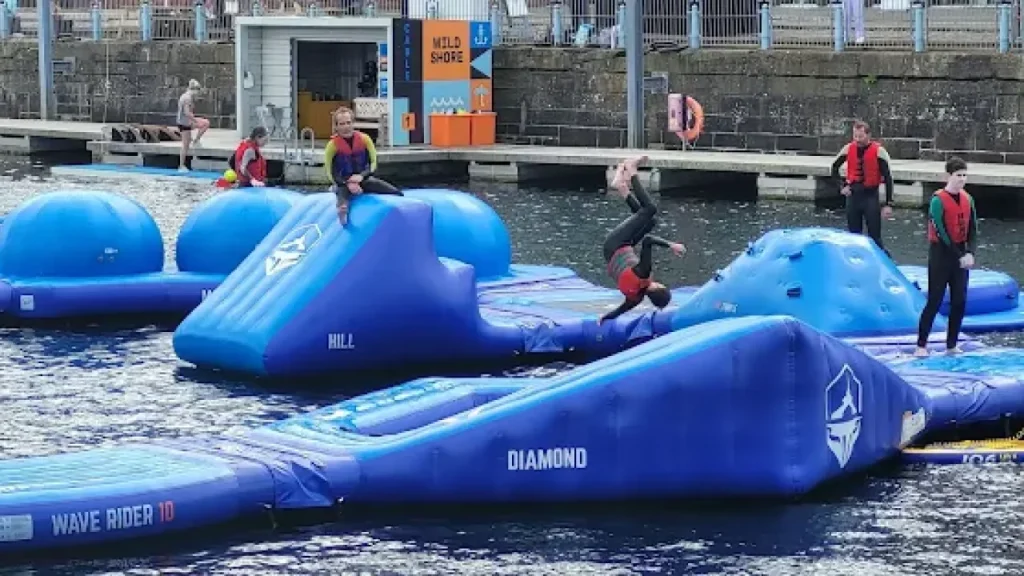 Kids flipping and climbing on blue inflatables at Wild Shore Dundee water park.