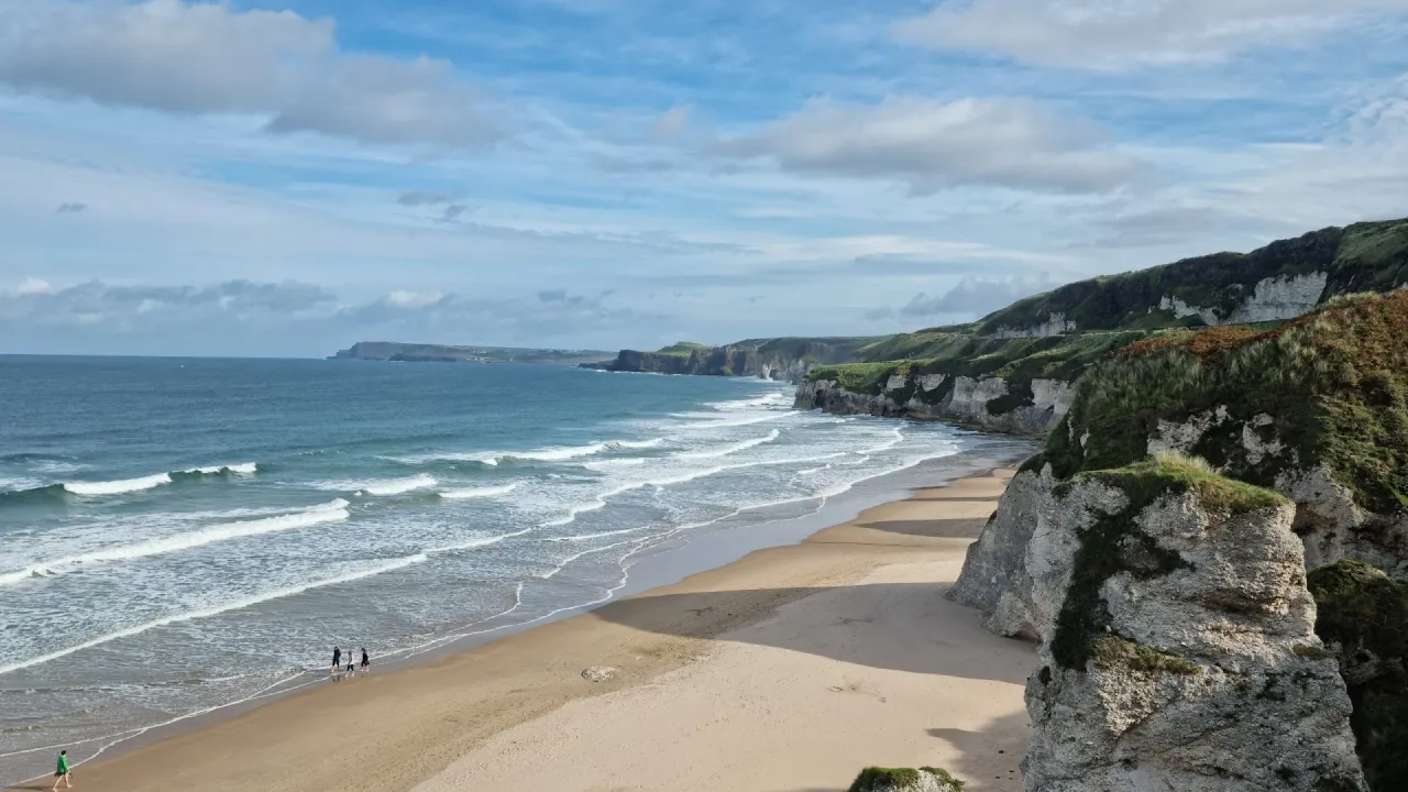 Whiterocks Beach on the Causeway Coast in Northern Ireland, with golden sand, rolling waves, and dramatic limestone cliffs.