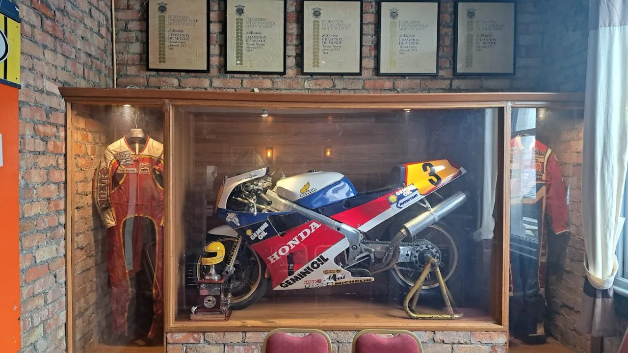 Display case inside Joey’s Bar in Ballymoney, featuring Joey Dunlop’s Honda racing bike, racing leathers, and trophies.