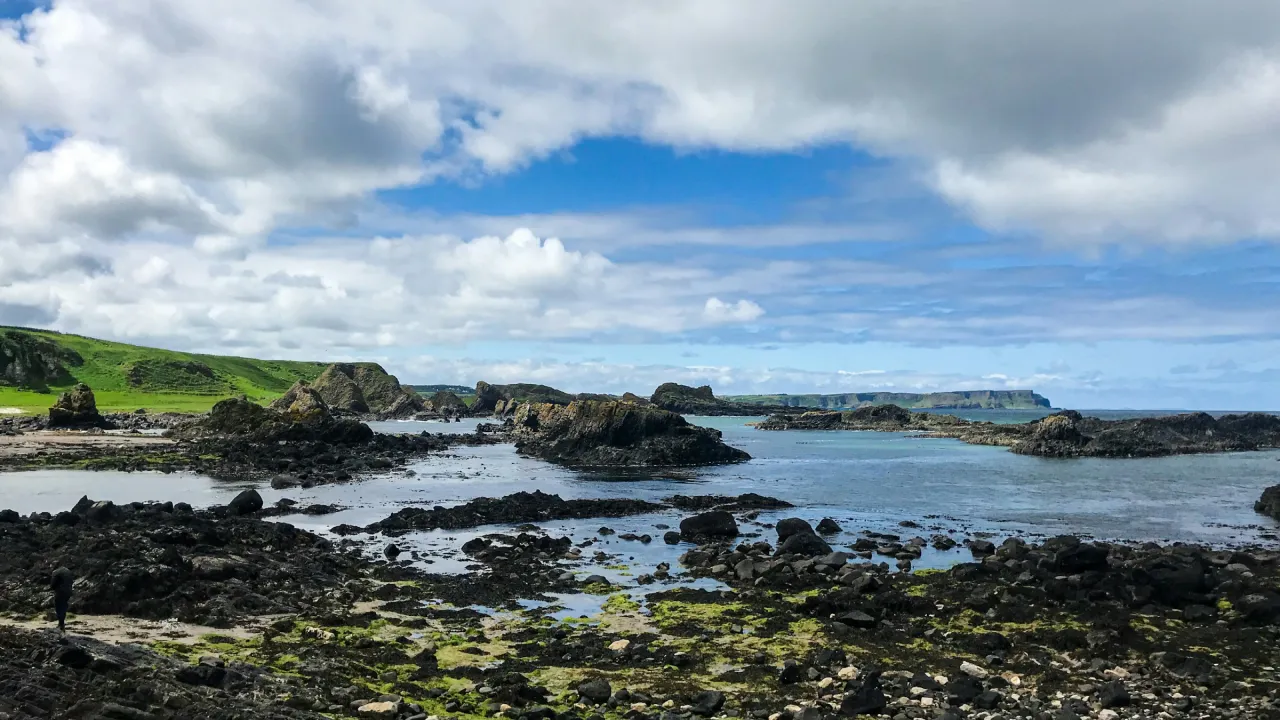 Causeway Coast and Glens in Northern Ireland, featuring rocky shoreline, green cliffs, and sweeping views over the North Atlantic Ocean.