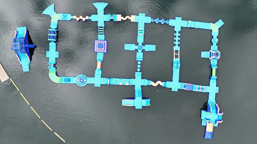 Aerial view of the Aqua Action inflatable obstacle course layout floating on Fairlop Waters, showing connected blue platforms and obstacles forming a loop.