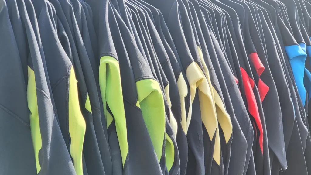 Rack of wetsuits in different sizes and colours ready for Aqua Action at Fairlop Waters, showing the hire equipment used for the inflatable aqua park sessions.